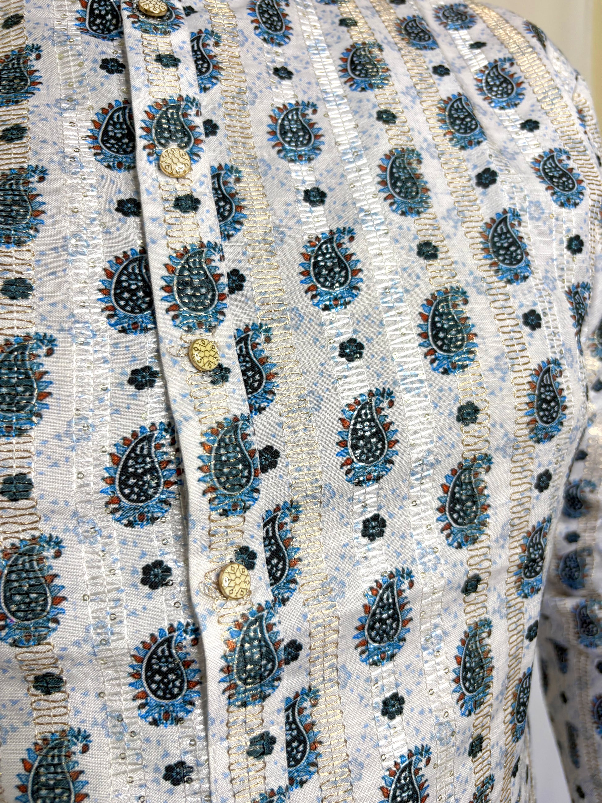 Close-up of blue and gold paisley print with buttoned placket on white rayon kurta – traditional fabric detail