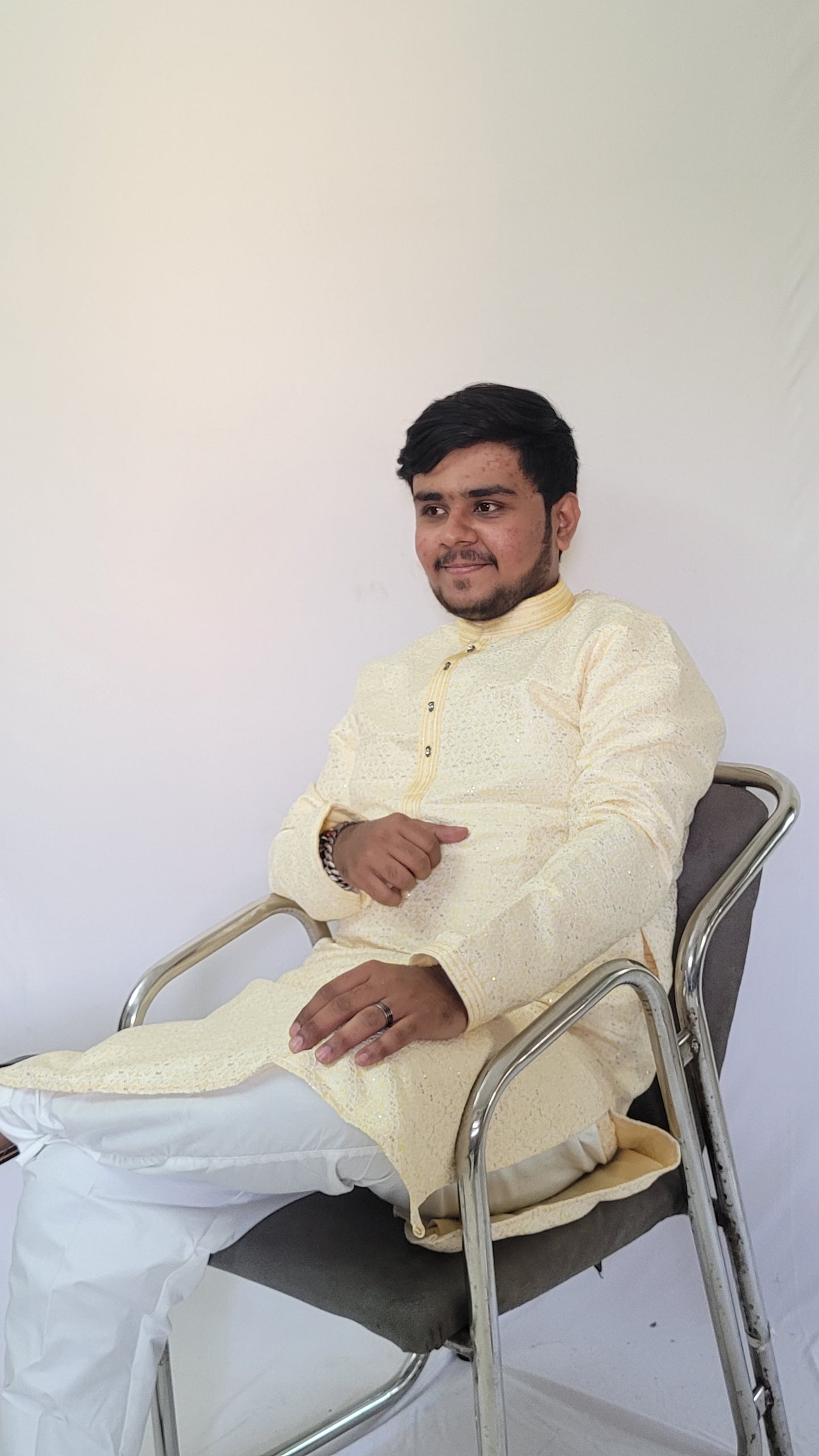 Close-up from seated left angle showing golden piping and jacquard weave on ivory sequin kurta